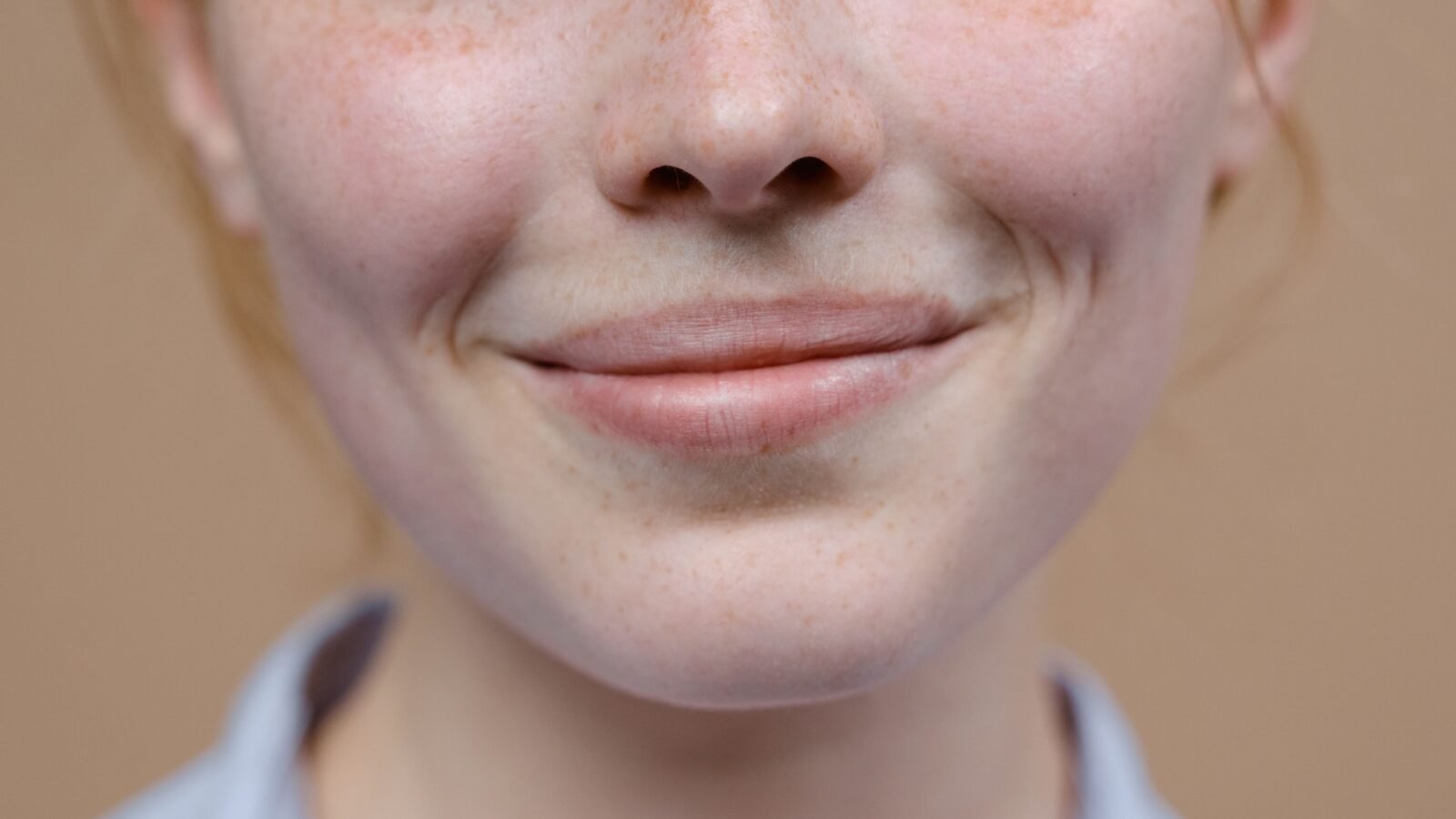 A woman laughing genuinely with natural skin texture, no makeup, in soft natural light