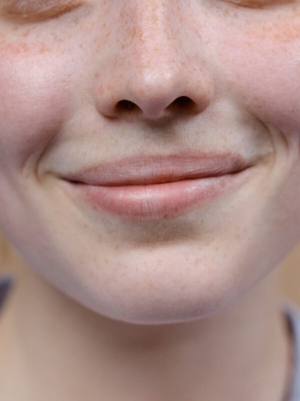 A woman laughing genuinely with natural skin texture, no makeup, in soft natural light